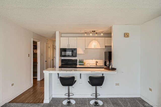 1020 15th St Unit 20F, Denver, CO 80202 - kitchen featuring baseboards, a breakfast bar, a sink, a peninsula, and black appliances
