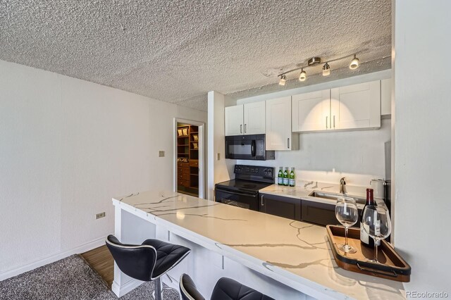 1020 15th St Unit 20F, Denver, CO 80202 - kitchen featuring a breakfast bar, white cabinetry, baseboards, light stone countertops, and black appliances