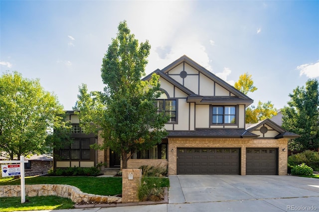 tudor home featuring driveway, stucco siding, an attached garage, and brick siding