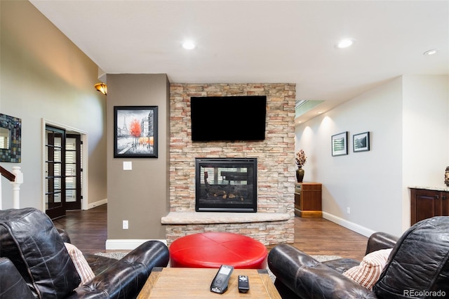 living room with recessed lighting, a stone fireplace, baseboards, and wood finished floors