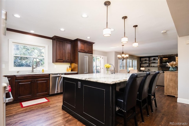 kitchen featuring appliances with stainless steel finishes, a sink, an island with sink, and dark wood-style floors