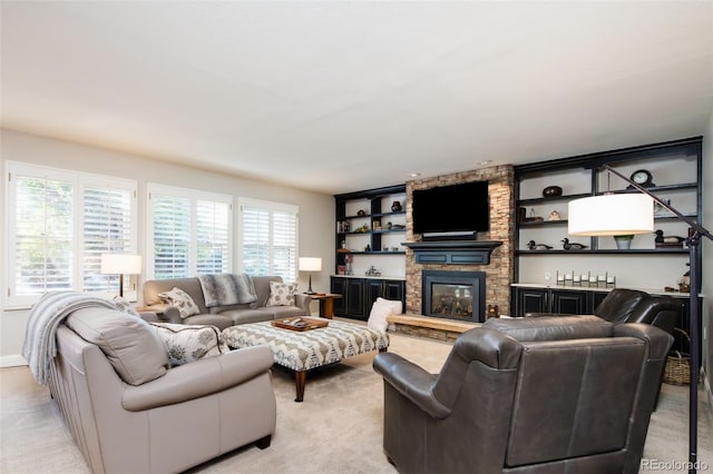 living area with a healthy amount of sunlight, light colored carpet, and a stone fireplace