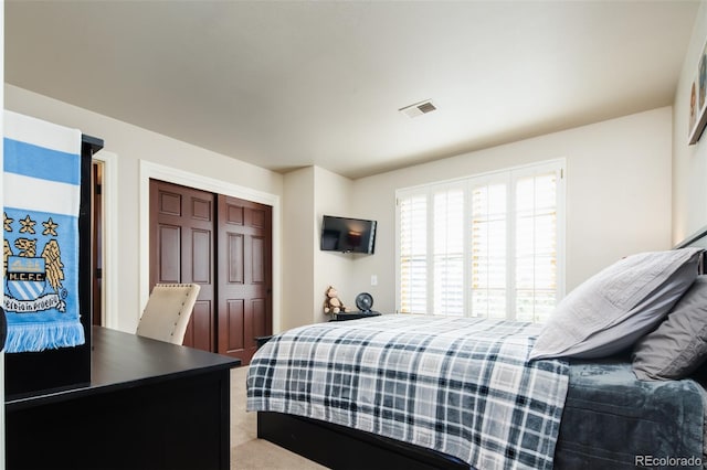 bedroom featuring a closet, visible vents, and light colored carpet