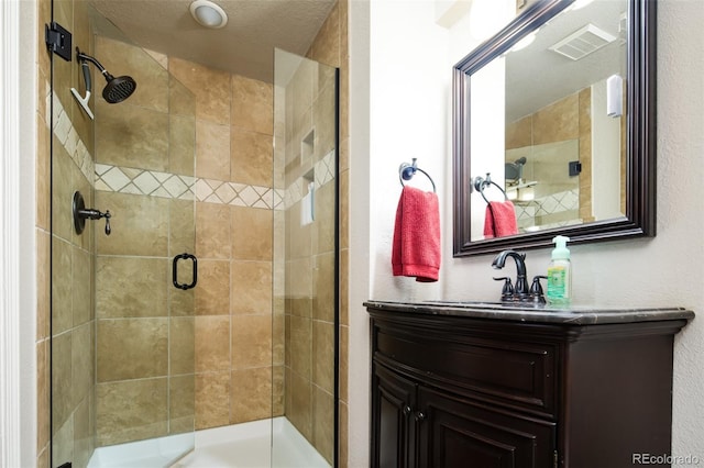 full bath featuring vanity, a shower stall, and visible vents