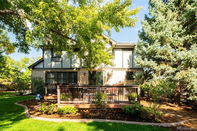 rear view of property featuring a yard, brick siding, and a wooden deck