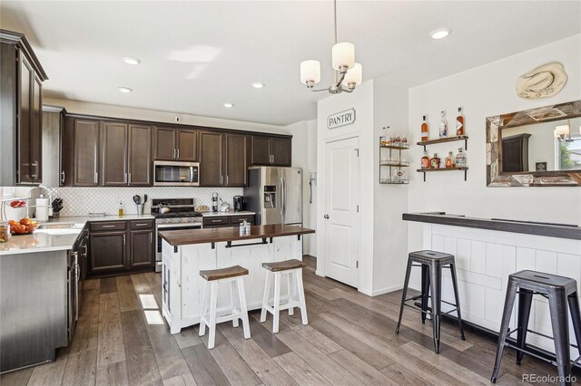 1846 Osprey Dr, Brighton, CO 80601 - kitchen with appliances with stainless steel finishes, dark brown cabinetry, a sink, dark wood-type flooring, and a kitchen breakfast bar
