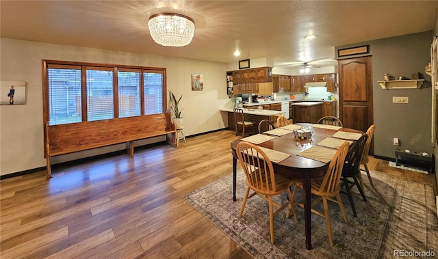 dining room featuring baseboards, wood finished floors, and ceiling fan with notable chandelier