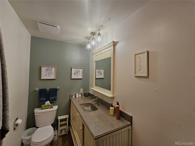 half bathroom featuring toilet, wood finished floors, and vanity