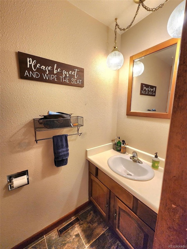 bathroom featuring visible vents, baseboards, and vanity