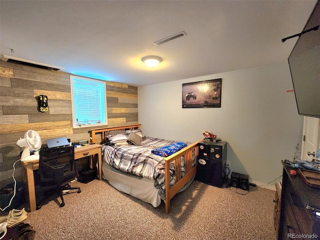 carpeted bedroom featuring wood walls and visible vents