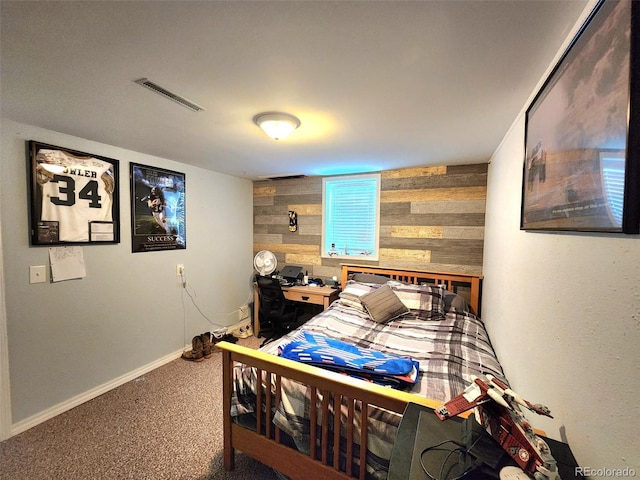 carpeted bedroom featuring visible vents and wood walls