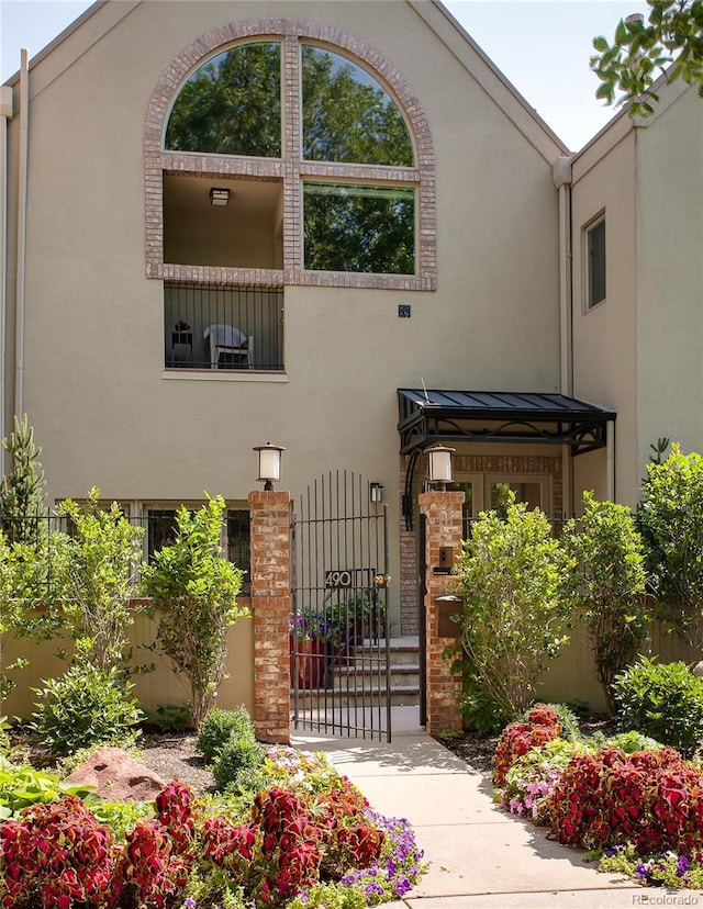490 Columbine St Unit 5, Denver, CO 80206 - view of front facade with stucco siding, a gate, a standing seam roof, a metal roof, and brick siding