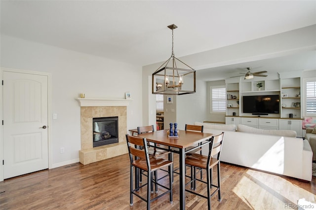 4542 Valleybrook Dr, Highlands Ranch, CO 80130 - dining space with a tile fireplace, wood finished floors, a chandelier, ceiling fan, and baseboards