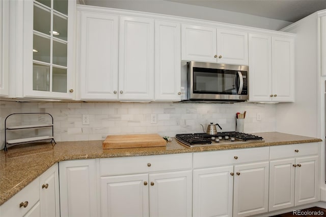 4542 Valleybrook Dr, Highlands Ranch, CO 80130 - kitchen with stainless steel appliances, white cabinets, glass insert cabinets, and tasteful backsplash