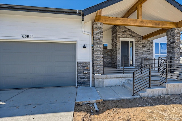 doorway to property featuring stone siding, covered porch, and an attached garage