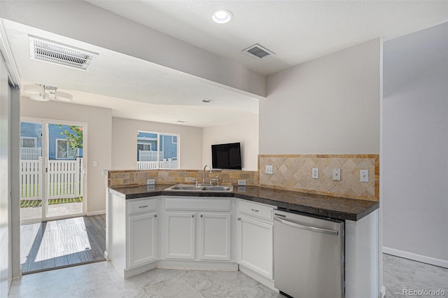 18954 E 57th Pl Unit D, Denver, CO 80249 - kitchen featuring stainless steel dishwasher, a peninsula, white cabinetry, dark countertops, and backsplash