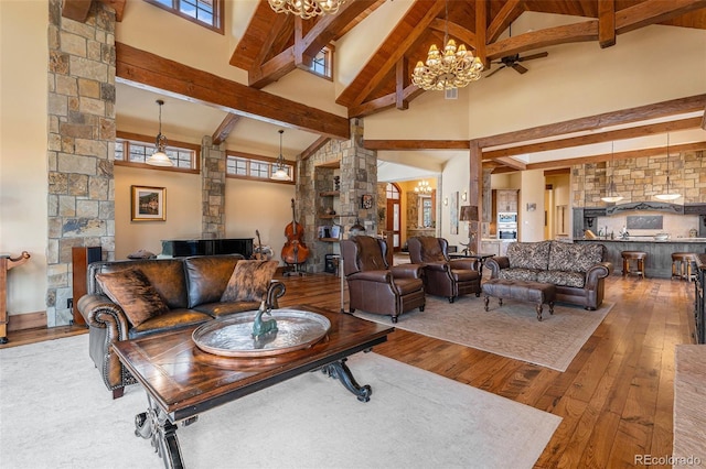 living room featuring hardwood / wood-style floors, ceiling fan with notable chandelier, beam ceiling, and high vaulted ceiling