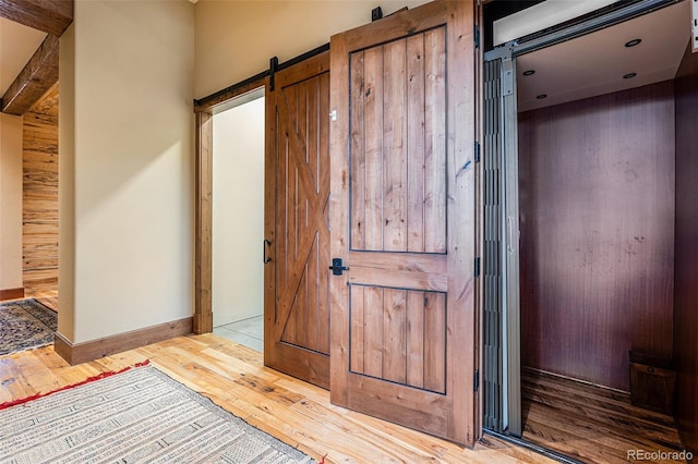 corridor featuring a barn door and light wood-type flooring