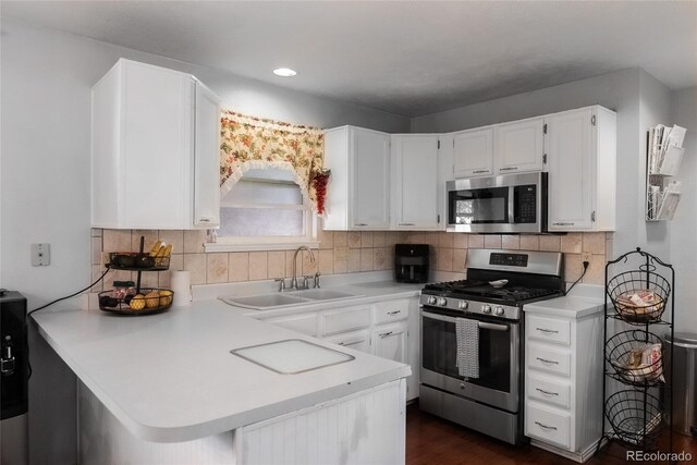 kitchen featuring tasteful backsplash, stainless steel appliances, white cabinetry, sink, and kitchen peninsula