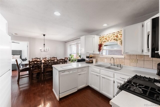 kitchen featuring white cabinetry, sink, white dishwasher, hanging light fixtures, and dark hardwood / wood-style flooring