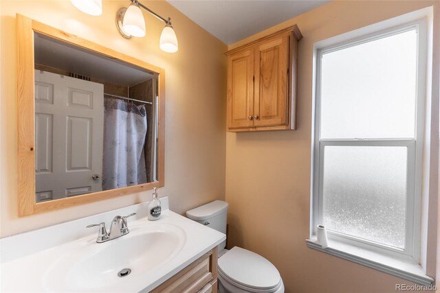 bathroom with curtained shower, vanity, and toilet