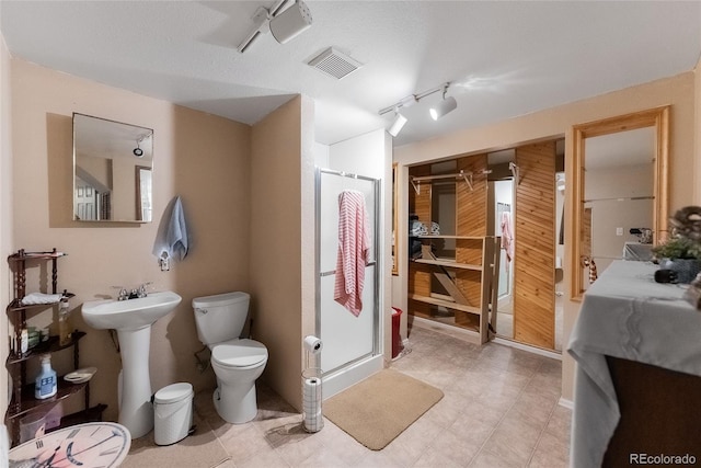 bathroom with a shower with door, toilet, and sink