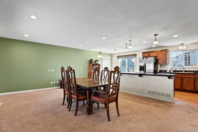 carpeted dining space with a textured ceiling and sink