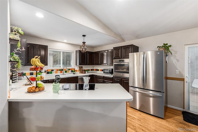 kitchen with lofted ceiling, sink, dark brown cabinets, stainless steel appliances, and decorative light fixtures