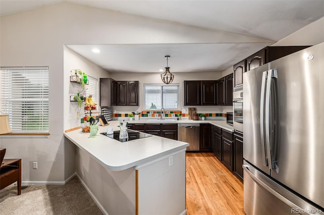 kitchen with pendant lighting, lofted ceiling, stainless steel appliances, and kitchen peninsula