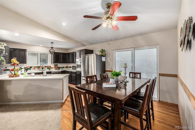 dining area with ceiling fan, vaulted ceiling, and light wood-type flooring