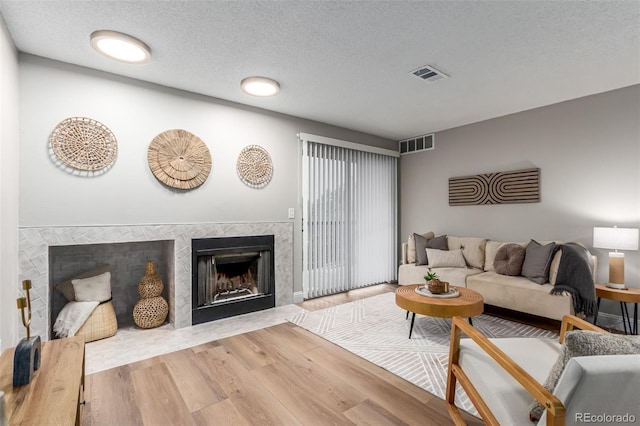 living room featuring a high end fireplace, wood finished floors, and a textured ceiling