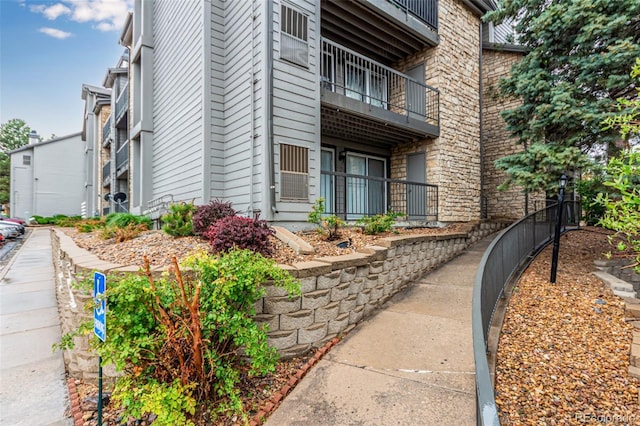 view of property exterior featuring a balcony and stone siding