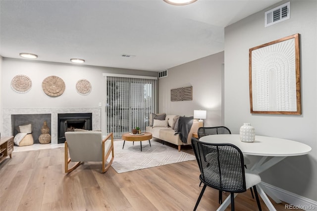 living room featuring light wood-style floors, a high end fireplace, and baseboards