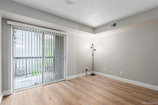 spare room with healthy amount of natural light, baseboards, light wood-style flooring, and a textured ceiling