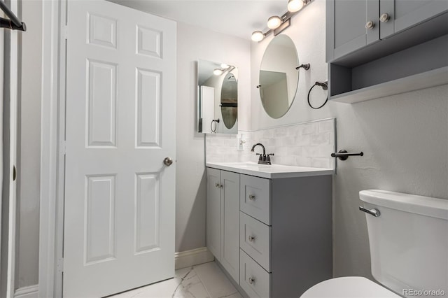 bathroom with toilet, tasteful backsplash, marble look tiles, vanity, and baseboards