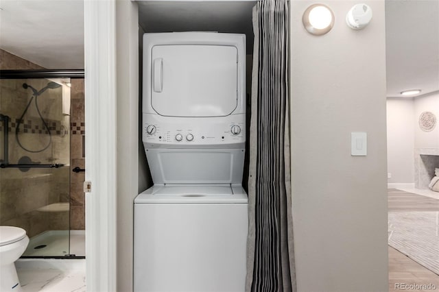 washroom featuring stacked washer and clothes dryer and baseboards