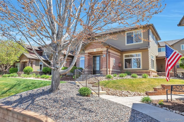 craftsman house featuring brick siding and a front lawn