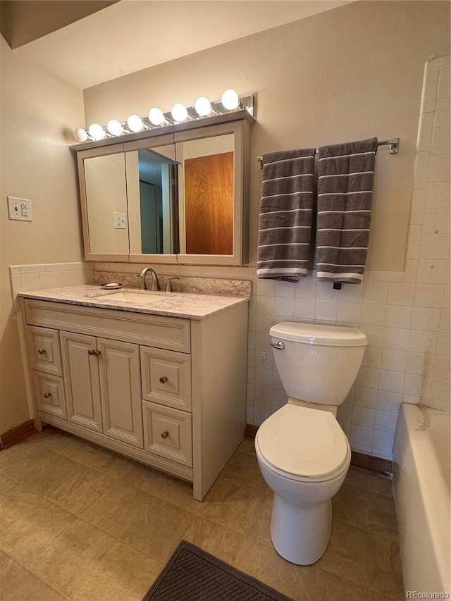 bathroom featuring vanity, tile walls, toilet, and a washtub
