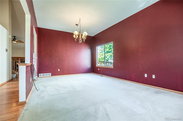 empty room featuring ceiling fan with notable chandelier, a brick fireplace, and light hardwood / wood-style flooring