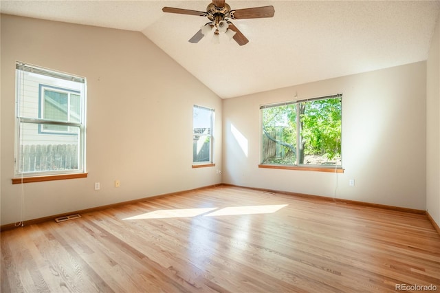 spare room with light hardwood / wood-style floors, vaulted ceiling, a textured ceiling, and ceiling fan