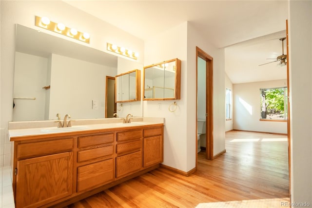 bathroom with wood-type flooring, vanity, toilet, and ceiling fan