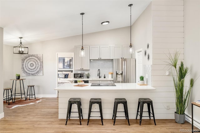 kitchen with white cabinetry, vaulted ceiling, a kitchen breakfast bar, tasteful backsplash, and appliances with stainless steel finishes