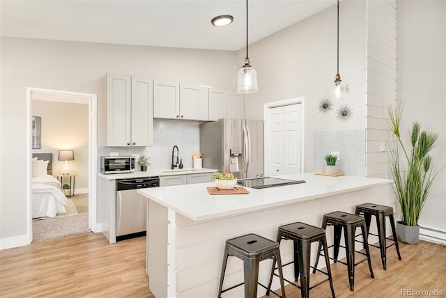 kitchen featuring sink, white cabinets, lofted ceiling, a breakfast bar area, and appliances with stainless steel finishes