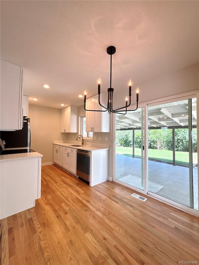 8239 Nola Dr, Denver, CO 80221 - kitchen with stainless steel dishwasher, freestanding refrigerator, a chandelier, light wood-style flooring, and white cabinets
