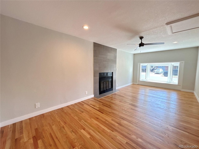 8239 Nola Dr, Denver, CO 80221 - unfurnished living room with light wood-style flooring, a tiled fireplace, a textured ceiling, recessed lighting, and a ceiling fan