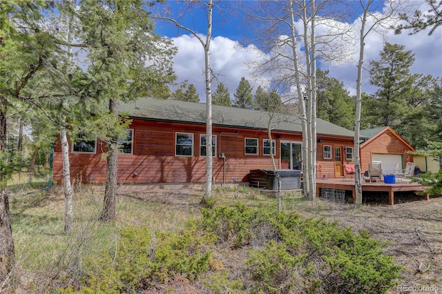 back of property with a hot tub and a wooden deck