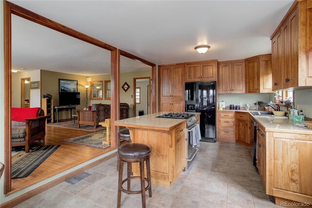kitchen with light countertops, stainless steel gas stove, black fridge, and a kitchen island