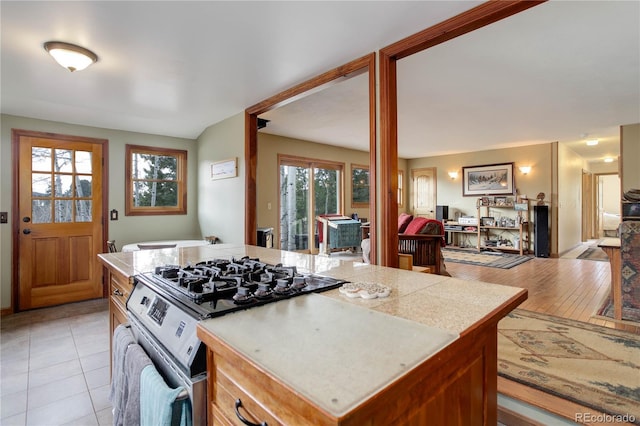 kitchen featuring light countertops, light tile patterned floors, gas stove, and open floor plan
