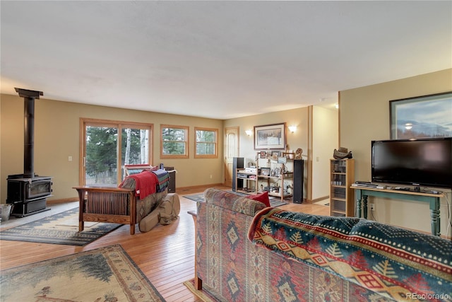living area featuring light wood-type flooring, a wood stove, and baseboards