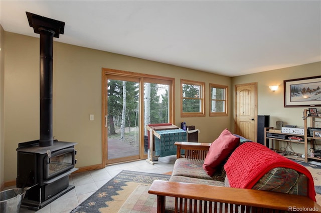 living area with a wood stove, baseboards, and light tile patterned floors